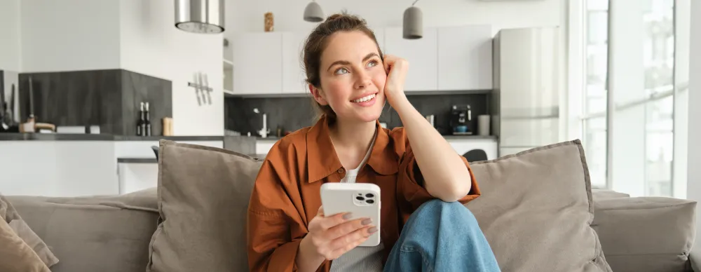 Frau sitzt auf dem Sofa und bestellt mit dem Smartphone Essen