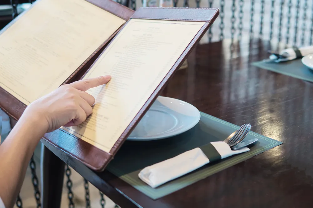 Frau liest im Restaurant die Speisekarte
