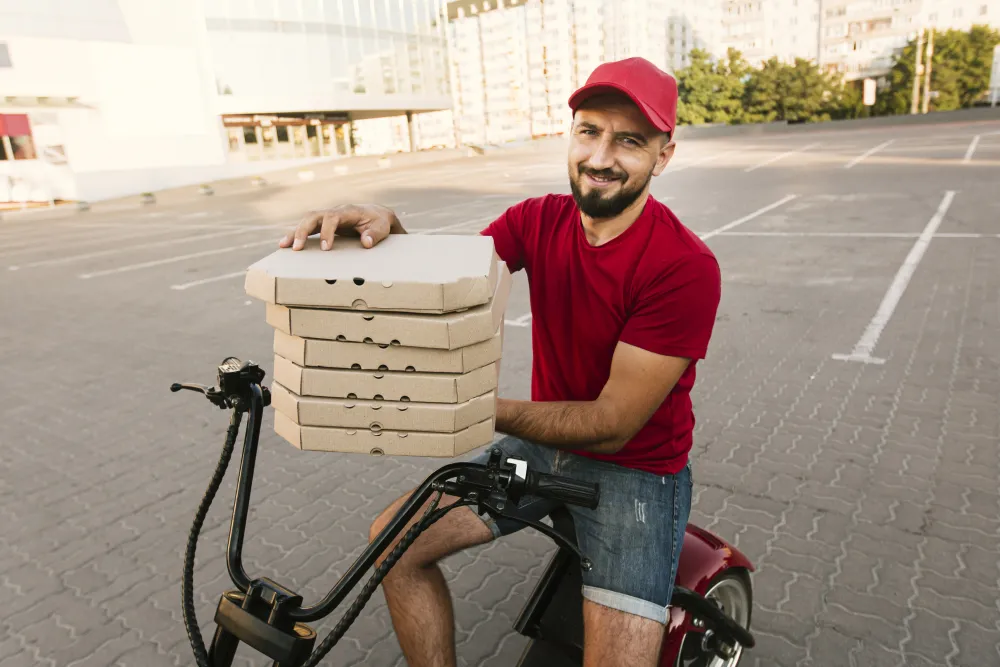 Lieferfahrer mit Thermobox auf einem Motorroller in der Stadt