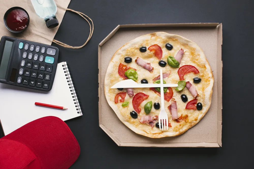 Pizzakarton neben einem Taschenrechner von oben