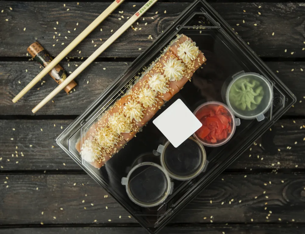 Sushi-Rollen mit Lachs, Wasabi und Ingwer in einer Lieferbox