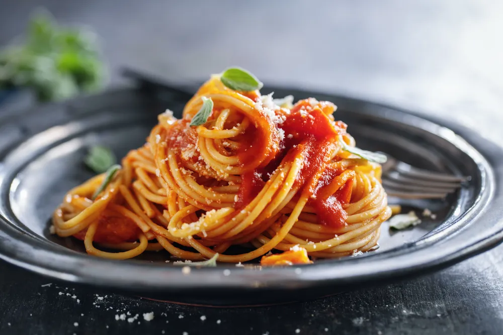Teller mit Spaghetti und Tomatensauce auf einem Tisch
